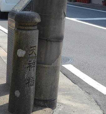 道路脇に「天神橋」と彫られた石碑が建っている写真