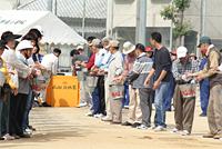 間を開けて向かい合って2列に並び、バケツを順番に回して消火活動を行っている校区防災訓練に参加した人達の写真