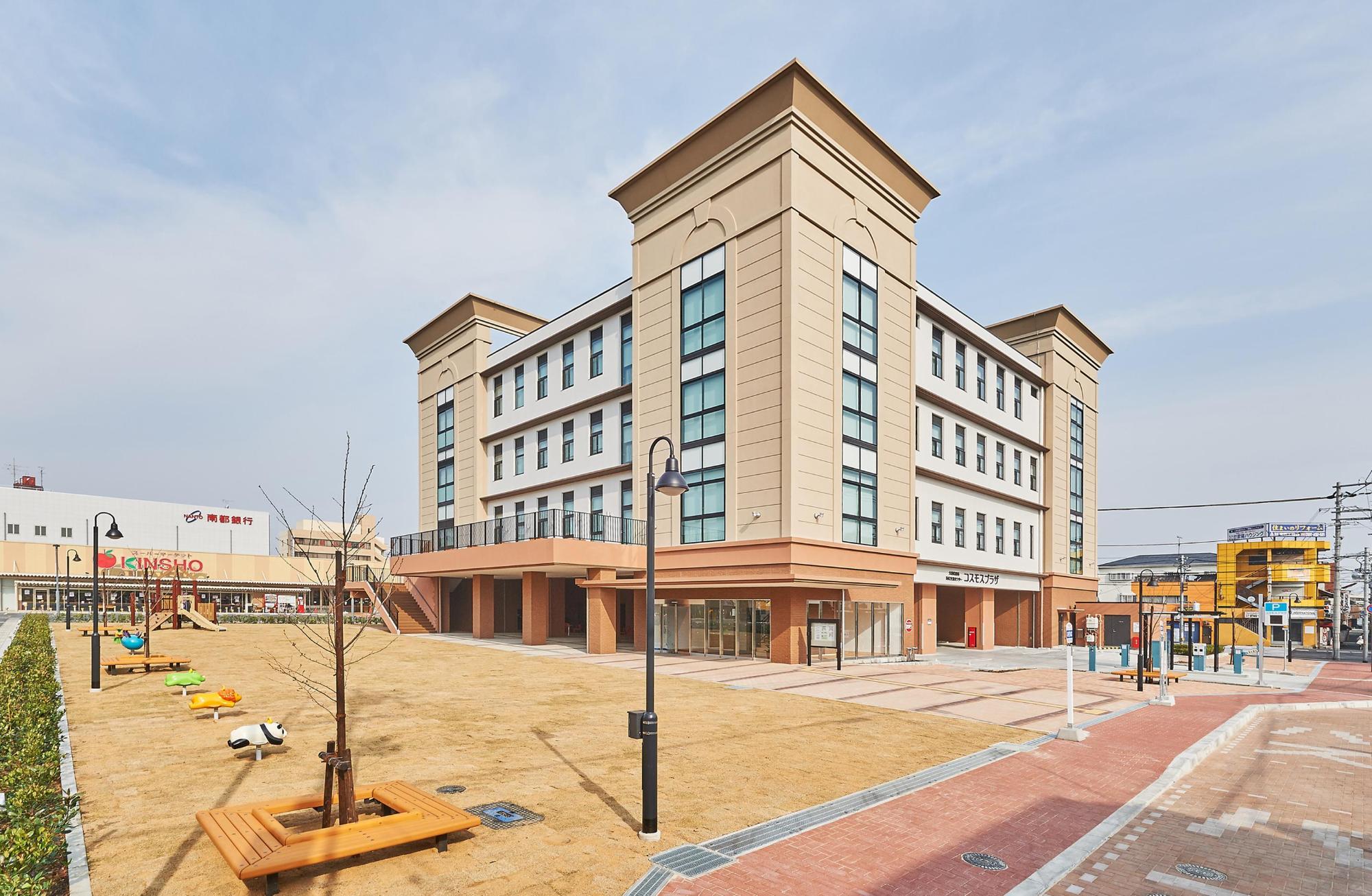 外壁をベージュ色やオフホワイト色を基調とした、4階建ての市民交流センターの建物外観の写真