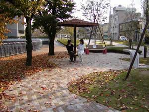 木々が植えられた遊歩道の奥の東屋で女性2人が座っている馬冷池公園の写真