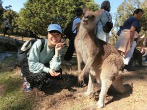 カンガルーの隣に座りピースをしている女の子の写真