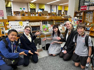 市立図書館で姉妹都市交流記念モニュメントの置物を中心にリズモー学生が囲んで並んでいる様子