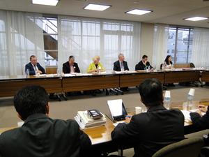 会議室で向かい合わせに並べられた席の窓側に座っている外国人6名の写真