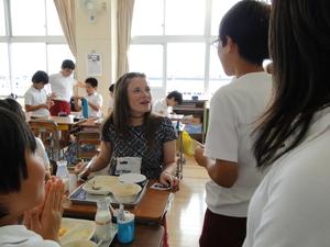給食時間に席に座っているリズモー市の女子学生に男の子が話しかけている写真