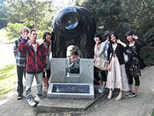 記念碑の前で8名の男女が記念写真を写している写真