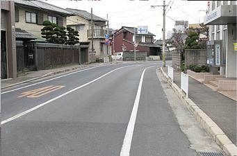 きれいに舗装された道路の緩やかなカーブの道を両脇の建物と一緒に写した写真