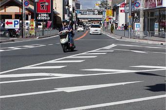 交差点に進入してくる原付と車が映された風景写真