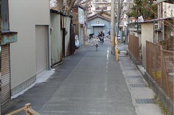 舗装された道路の奥から自転車に乗った子供が向かってきている写真