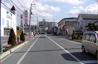 左手に眼鏡屋さんの店舗と看板がある道路を写した写真