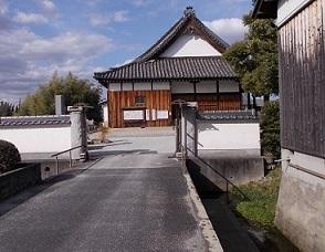 入り口の門から入ってすぐの三角形の瓦屋根の正行寺の建物を、細い通りの道から撮影した写真