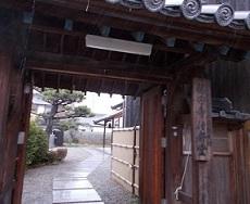 門の右側に福田寺と書かれた年季の入った木製看板が掛けられている寺の入り口の写真