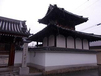 入り口右側に善教寺と書かれた石碑が立っている、瓦葺屋根の寺の門の写真