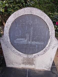 丸い形をした石に記念の文字と建物の絵が描かれているユニチカ記念碑の写真