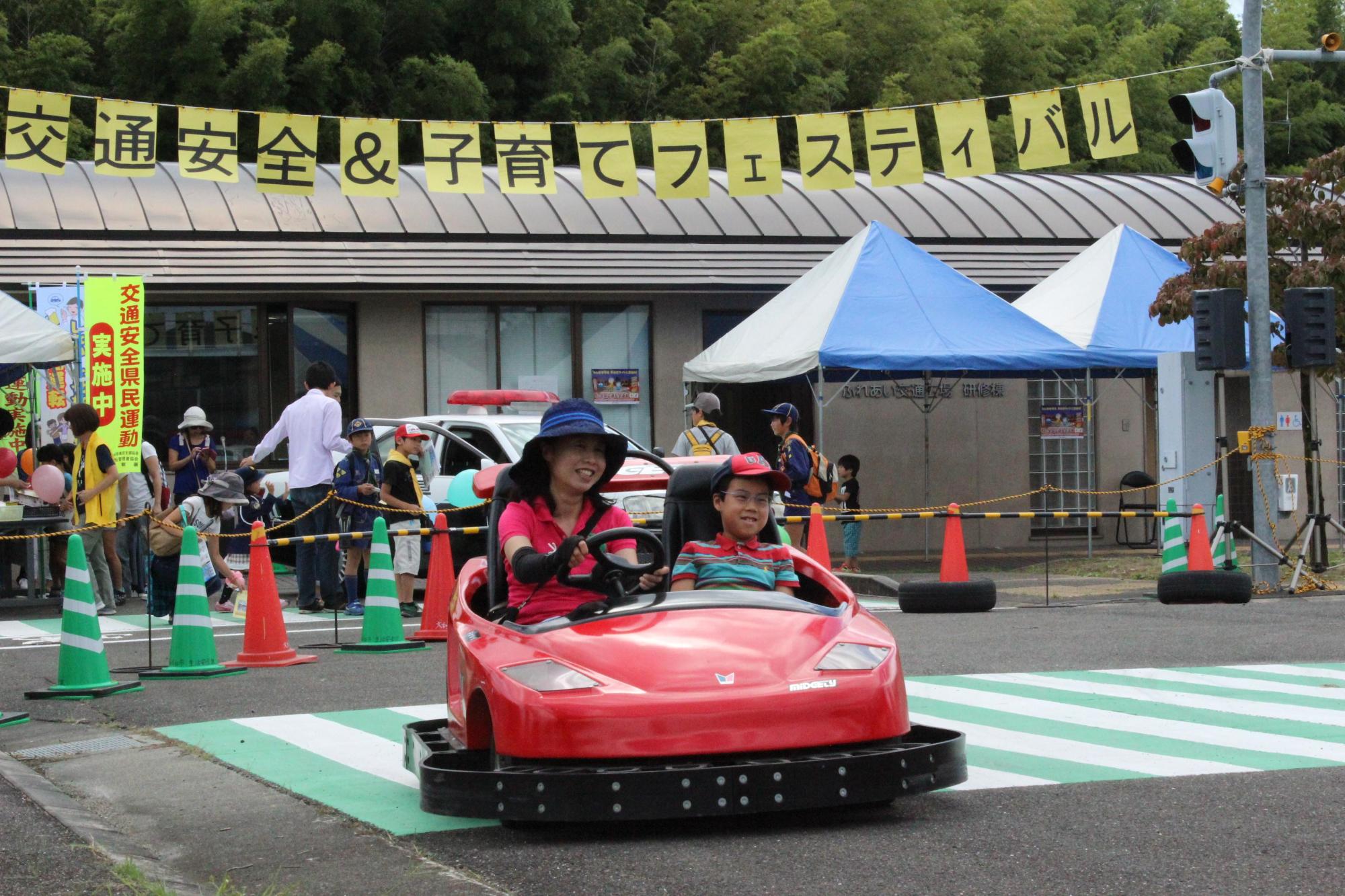 来場した親子が楽しそうに赤いゴーカートを運転している写真