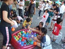 子どもたちがビニールプールの周りに集まりボールすくいをしている写真
