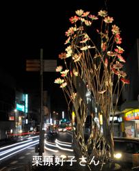 暗がりのなか、車のライトの光線と手前の花のオブジェがライトに照らされたのを写した写真部門の大賞受賞作品