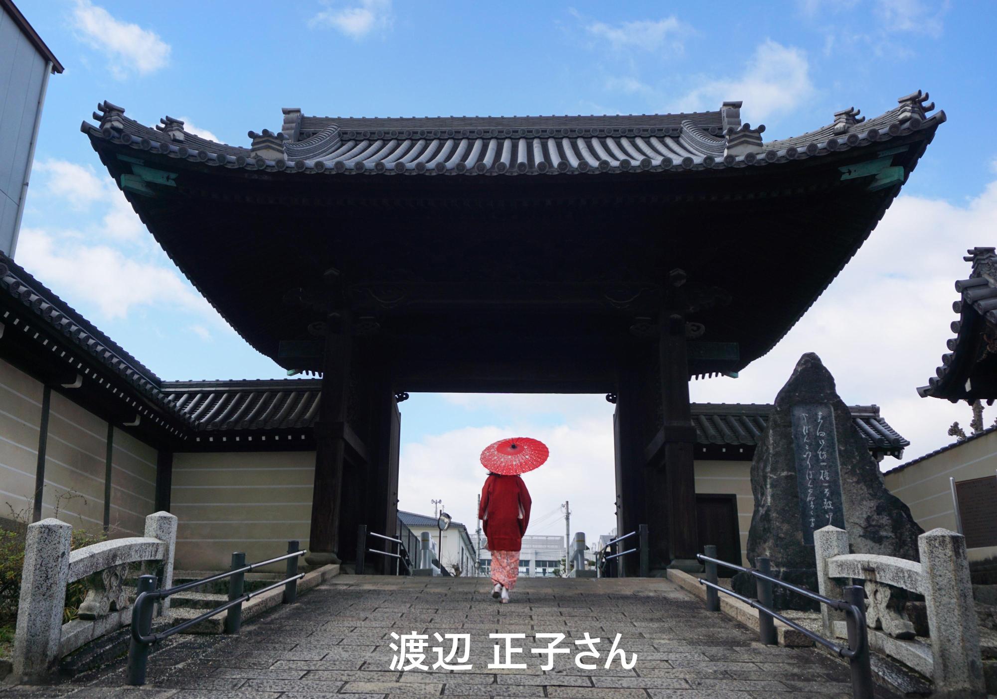 お寺の楼門の下を歩く、薄ピンク色の着物に赤色の和傘を差した女性の後ろ姿を写した写真部門の大賞受賞作品
