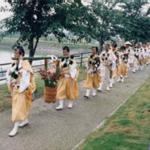 大きな木桶に入った蓮華の花を担いで、池の遊歩道を練り歩いている修験者一行の写真