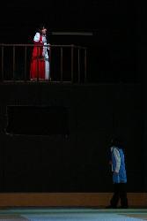 ベランダの上で赤と白の衣装を着たジュリエットと、ベランダの下にいる青色の衣装を着たロミオが向かいあって立っている一場面の写真