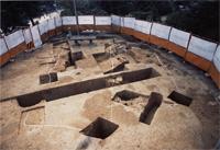 ところどころ白線で印がされ、発掘調査の穴が掘られた跡が見られる円形の古墳の中を高台から撮影した写真