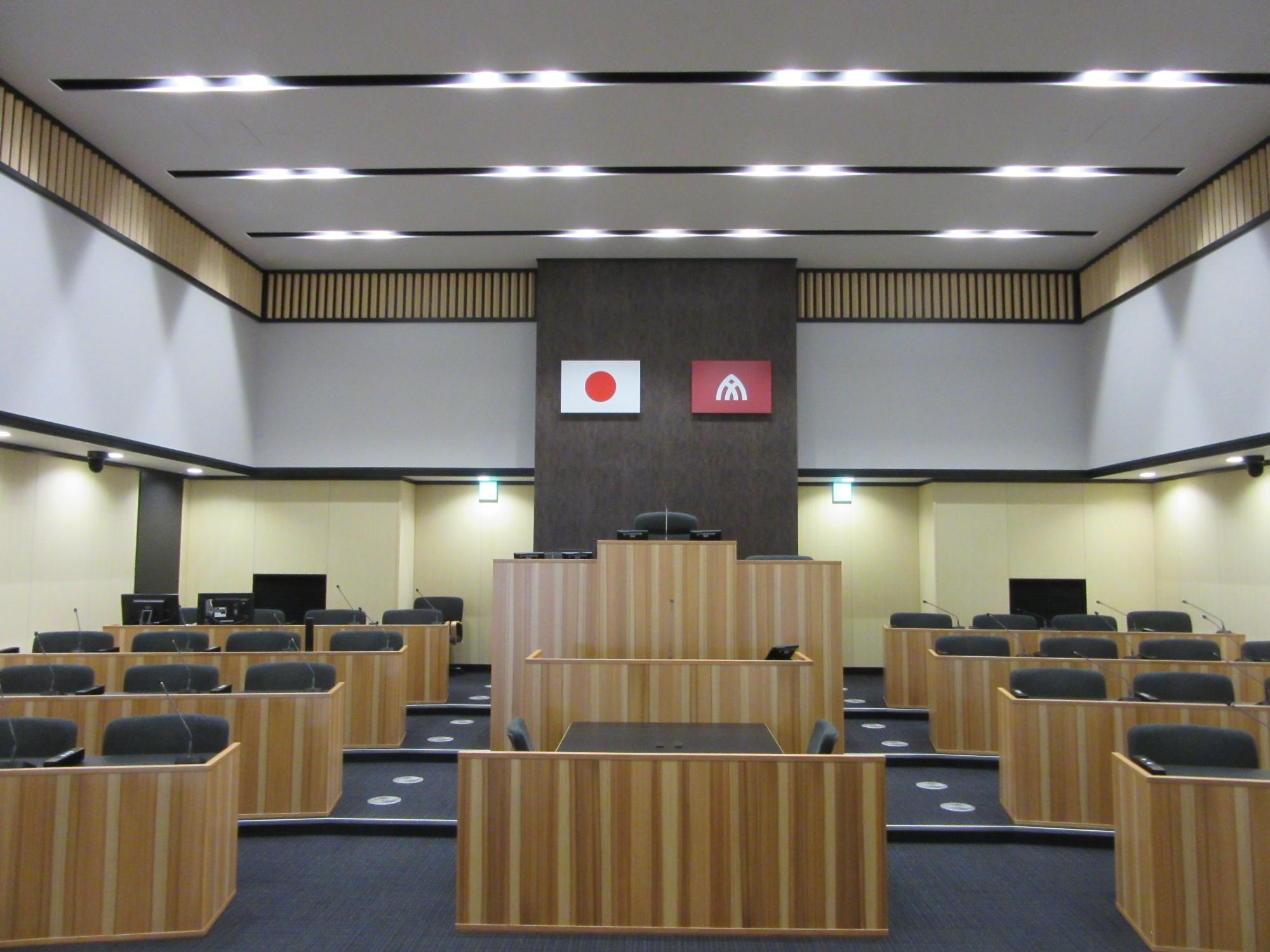 国旗と大和高田市の市章が掲げられてある議会室の写真