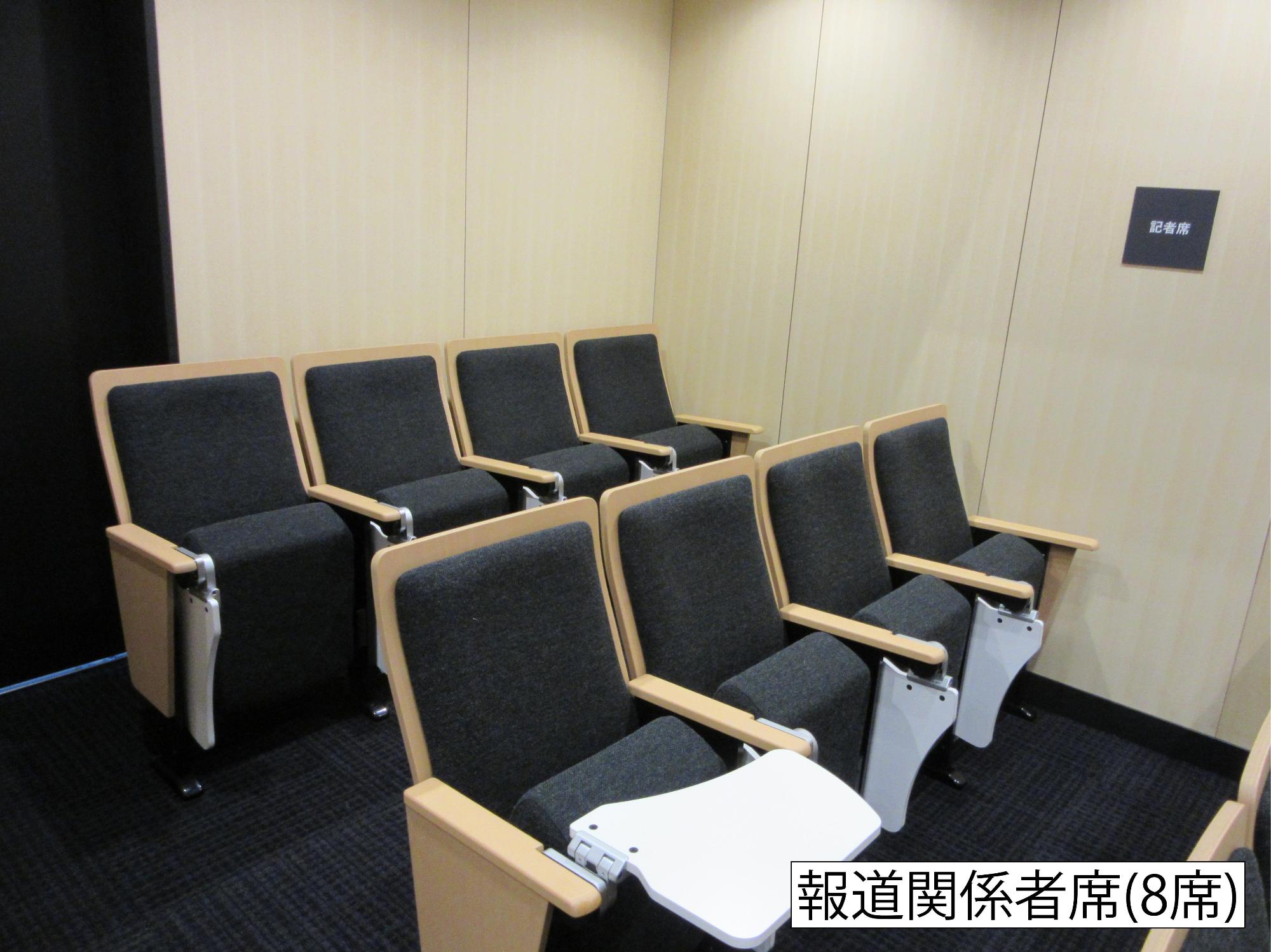 前に4席、後ろに4席の折り畳み可能な小さなテーブルが付いた8席の報道関係者席の写真