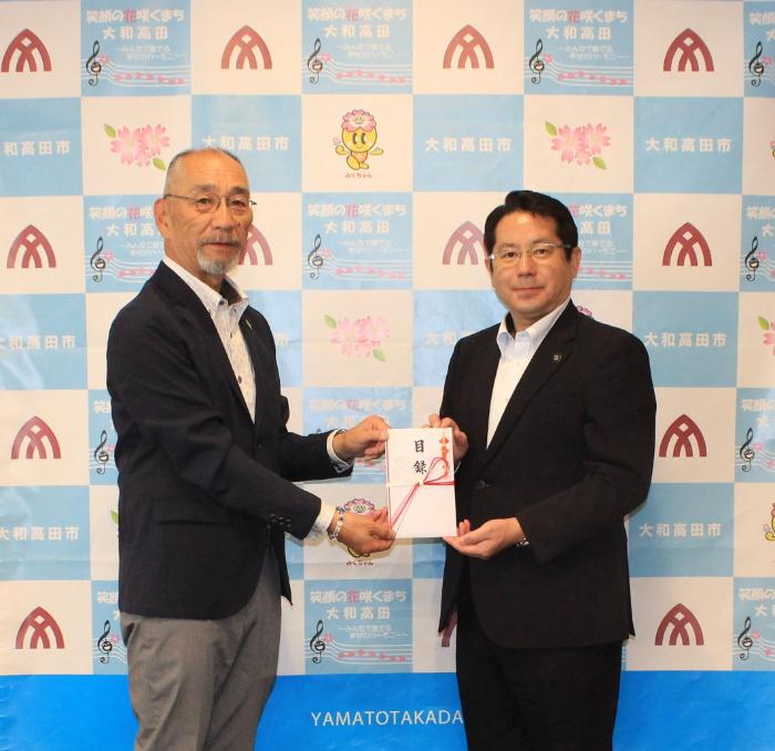 高田鋼材工業株式会社 松村代表取締役社長から堀内市長へ目録を手渡す画像