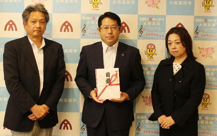 寄附目録贈呈式の模様（kss株式会社 営業部の佐藤正明部長(左)と堀内市長(真ん中)と村上敬子シーティングプランナー（右））