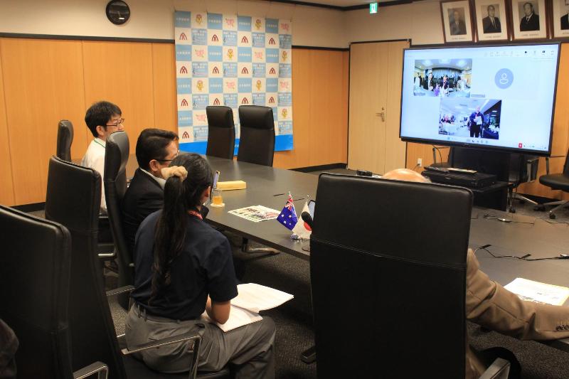 4人がテーブルに座り、テレビ画面を見ています。