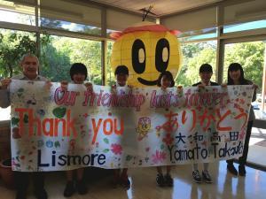 みくちゃんのランタンと「Our friendship lasts forever Thank you Lismore ありがとう 大和高田 Yamato.Takada」と書かれた旗を持っている学生5名と市長の写真