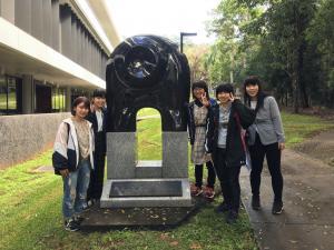 記念モニュメントの前で記念撮影をしている女子学生5名の写真