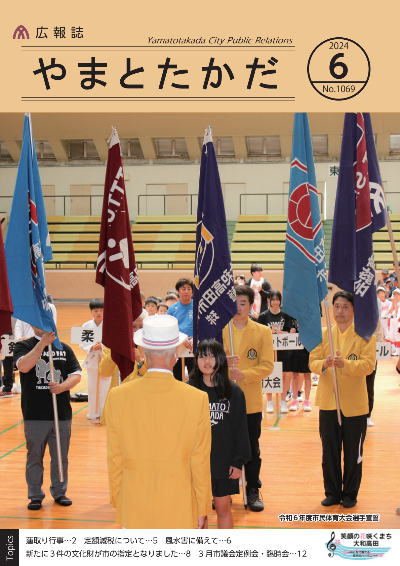 広報誌6月号表紙  令和6年度市民体育大会にて、バスケットボールに出場する女性の選手が選手宣誓をおこなっている様子。後ろには大きい旗を持った男性が並んでいる。