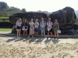 リズモー市から6名の学生と1名の引率者が大きな岩の前で記念撮影をしている写真
