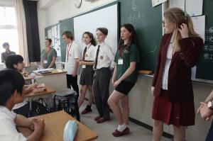 リズモー市からの6名の学生が制服姿で高田商業高校教室の黒板前に並び生徒に挨拶をしている写真