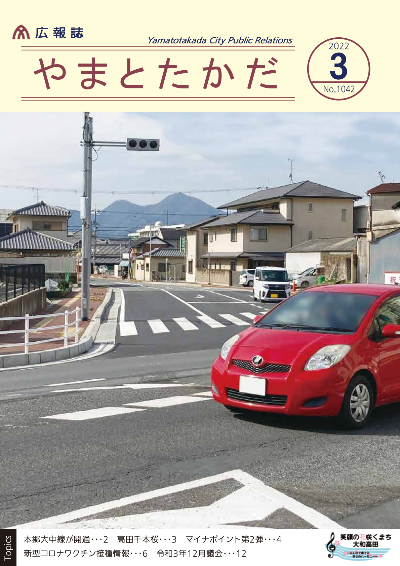 広報誌3月号表紙 開通した本郷大中線を走る赤い車の写真