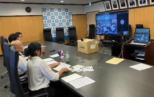 4人の人がテーブルで並びに座り、テレビの画面に向いている様子