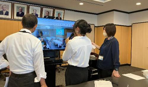 3人の者が立っていて、テレビの画面に向いている様子