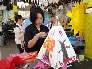 女の子が木の絵と「秋」「冬」と書かれたランタンを作成している写真