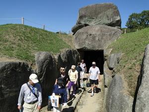 大きな岩が置かれた下にトンネルがある道を歩いているリズモー市の学生たちの写真