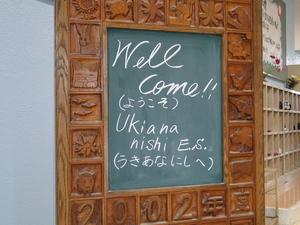 花や動物などが彫られた木のフレームの中央にある黒板に「welcome!!(ようこそ)Ukiana nishi E.S.(うきあなにしへ)」と書かれている写真