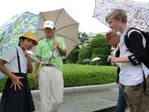 傘をさしながら女子学生に話しかけているリズモー市の男子学生の写真