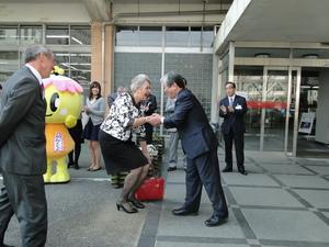 ジェニー・ドウェル市長と吉田市長が庁舎の前で握手を交わしている写真