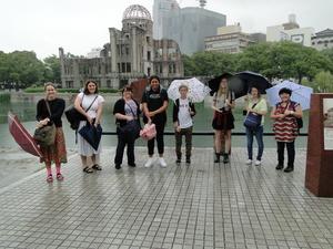 広島平和記念公園の原爆ドームをバックに記念撮影をしているリズモー市の学生7名と引率の先生の写真