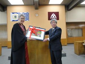 ジェニー・ドウェル市長と吉田市長がリボンのついた絵画を一緒に持っている写真