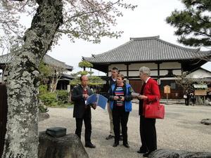 ジェニー・ドウェル市長、ギャリー・マーフィー氏、ミシェル・マーフィー氏が桜の木の前で手にファイルを持った日本人男性の説明を聞いている様子の写真