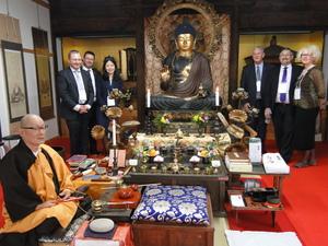 6名の外国人の人達が3人ずつに分かれ仏像の両脇に並び、手前に住職が座っている写真