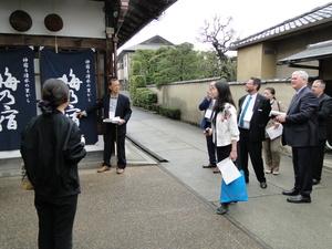 海乃宿と書かれた暖簾を説明している男性の案内を聞いている外国人参加者達の写真