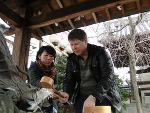 キャメロンさんが女性の方から木製の柄杓を受け取っている写真