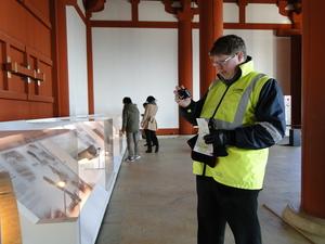 ガラスケースの中に展示されている展示物をカメラで撮影しているキャメロンさんの写真