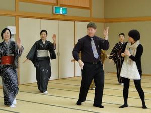 4人の着物を着た女性達と一緒に和室で日本舞踊を踊っているキャメロンさんの写真